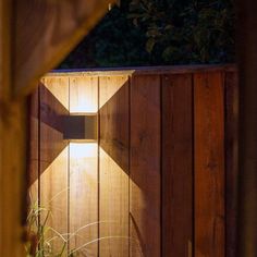 a wooden fence with a light shining on it and grass growing in the foreground