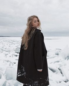 a woman standing in the snow wearing a black coat