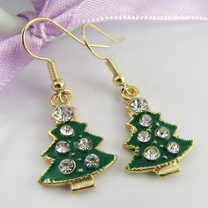 Fun Christmas Charm Hook Earrings with Enamel & Rhinestone Christmas Tree Charms       Materials:     Earring Hooks - Brass   Charms - Alloy & Enamel     Approx. Total Earring Length: 36 mm Gold Jewelry With Matching Earrings For Holiday, Green Jewelry For New Year Party, Green Jewelry For New Year's Party, Gold Jewelry For Winter Party, Gold Drop Earrings For Christmas, Gold Earrings For Holiday Season, Gold Dangle Jewelry For Christmas, Gold Earrings For New Year Holiday, Gold Earrings For Winter Holiday