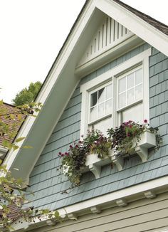 two flower boxes on the side of a house with white trim and blue shingles