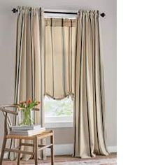 a chair and window in a room with striped drapes on the windowsills