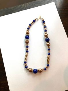 "Vintage Signed V.A. Navy and Bronze Beaded Necklace. The beads of this necklace are plastic. There are some gold tone spacers and bead caps. There are bronze small beads and larger beads and twisted beads. The navy blue beads are also a variety of sizes. The clasp is a simple hook signed V.A.  It is 18\" long. It looks like a heavier necklace then what it is. It is in excellent condition. No missing beads, no chips, no scratches or color discolor." Gold Necklaces With Polished Metal Beads, Gold Necklaces With Metal Beads, Gold Beaded Chain Metal Necklaces, Gold Metal Beaded Chain Necklace, Elegant Gold Metal Beaded Necklaces, Elegant Gold Beaded Necklaces With Metal Beads, Gold Metal Beads Necklace For Jewelry Making, Large Gold Beads For Costume Jewelry, Adjustable Costume Jewelry Beaded Necklace With Gold Beads