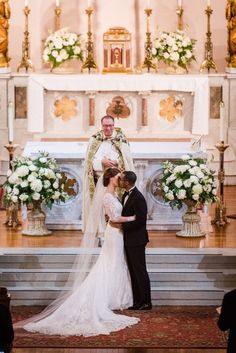 a bride and groom standing in front of the alter at their wedding ceremony with white flowers