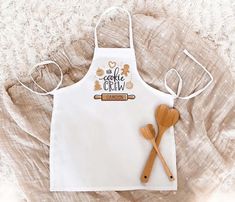 an apron and two wooden spoons are on the table next to a white towel