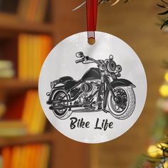 a christmas ornament hanging from a tree with a motorcycle on it's side