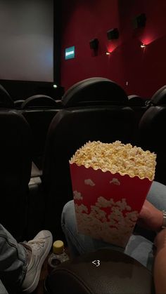 a person sitting in front of a screen holding a box of popcorn