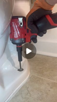 a person using a drill to fix a toilet