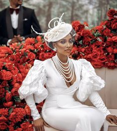 a woman sitting on top of a bench wearing a white dress and headpiece with pearls