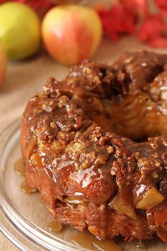 a glazed apple donut sitting on top of a glass plate