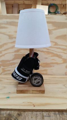 a lamp that is sitting on top of a wooden block with hockey gloves underneath it