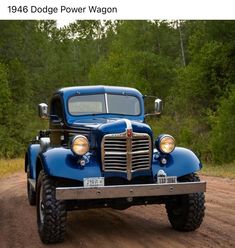 an old blue truck is parked on the side of a dirt road with trees in the background