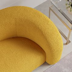 a yellow chair sitting on top of a white floor next to a vase filled with flowers