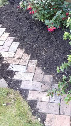 a fire hydrant sitting in the middle of a flower garden next to a brick walkway