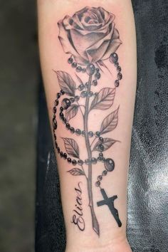 a rose and rosary tattoo on the arm