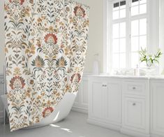 a bathroom with a bathtub, sink and shower curtain that has flowers on it