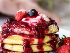 a stack of pancakes topped with berries and syrup