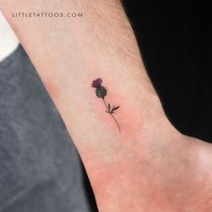 a small flower tattoo on the wrist is shown in this image, it looks to be purple