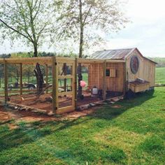 a small wooden structure in the middle of a field with trees and grass around it