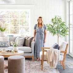 a woman standing in a living room next to a couch