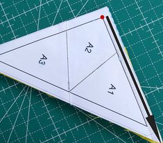 an origami sail sitting on top of a cutting mat