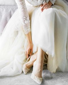 a woman sitting on top of a white couch wearing high heels and a dress with lace