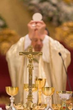 a man in a priest's robes is holding his hands up to the cross