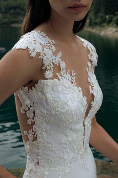 a woman in a wedding dress standing by the water