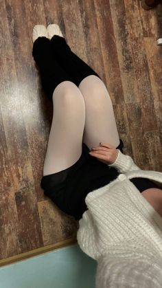 a woman laying on the floor with her legs crossed and wearing black stockings, tights and socks