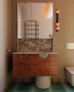 a bathroom with a sink, mirror and toilet in the corner next to a wall mounted light