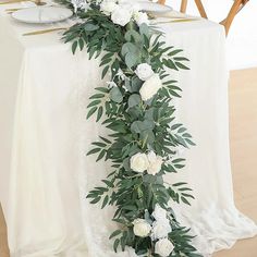 the table is set with white flowers and greenery