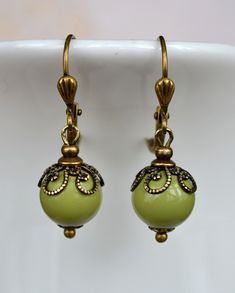 VINTAGE ELEMENTS Unique Jewellery, Handmade from Vintage Inspired, Original Designs Art Nouveau style antiqued brass earrings with pale Olive Green Glass drops and ornate filigree bead caps. These earrings are made with antiqued brass leverback earwires and measure 3.2cm from the top of the earwires. Vintage Green Brass Earrings, Art Nouveau Antiques, Glass Drop Earrings, Vintage Elements, Jewellery Handmade, Brass Earrings, Bead Caps, Green Glass, Antique Brass