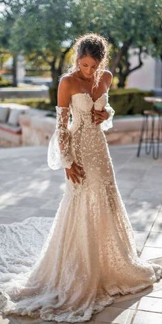 a woman in a wedding dress is looking down at her phone while standing on the sidewalk