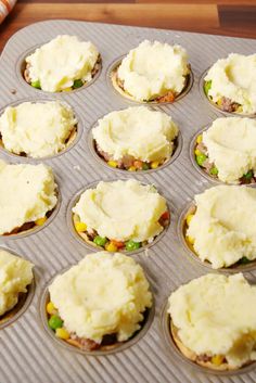 a muffin tin filled with cupcakes covered in mashed potatoes and meat