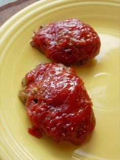 two pieces of meat covered in sauce on a yellow plate