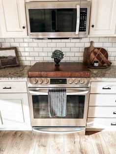 a kitchen with an oven, microwave and counter tops in white painted wood flooring