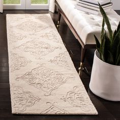 a large white rug in front of a window with a potted plant next to it