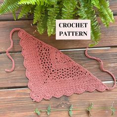 a crochet triangle is sitting next to a plant on a wooden surface with the text, crochet pattern