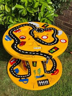 a yellow table with cars on it sitting in the grass