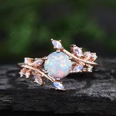 an opal and diamond ring sitting on top of a piece of wood