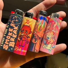 someone holding four different colored lighters in their hand with the same design on them