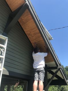 a man standing on the side of a house with his hands in the air and reaching up