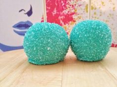 two blue and green cake balls sitting on top of a wooden table next to each other