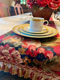 a table topped with a cup and saucer next to a vase filled with flowers