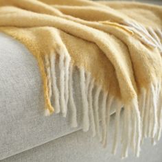 a yellow blanket is folded on the back of a couch