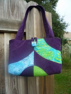 a purple and green bag hanging on a wooden fence