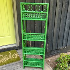 a green metal shelf sitting on top of a wooden floor next to a door and grass