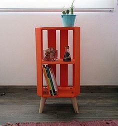 an orange book shelf with books on it and a potted plant in the corner