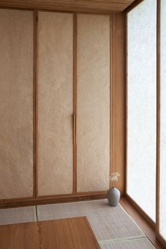 an empty room with wooden paneling and a vase on the floor next to it