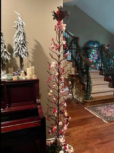 a decorated christmas tree sitting on top of a hard wood floor next to a stair case