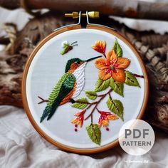 there is a embroidery pattern with two birds on the branch and flowers in the background